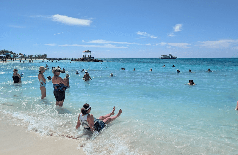 A group of women laughing and playing in the ocean surf on a tropical Caribbean beach.