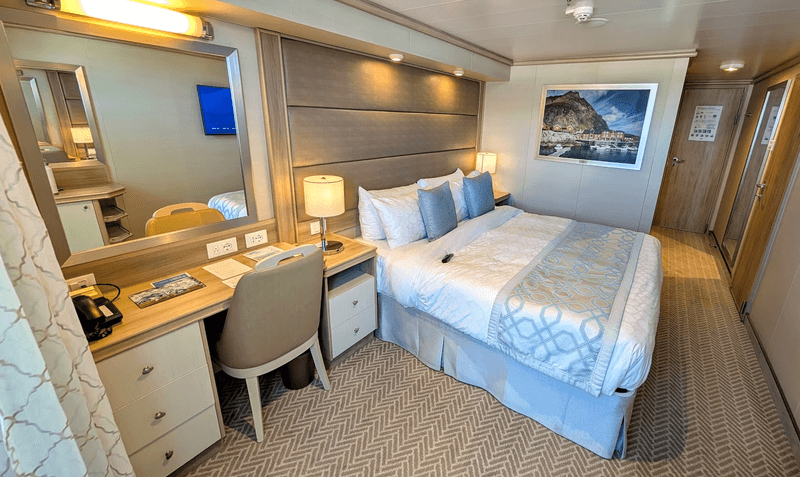 The modern and spacious interior of a balcony stateroom cabin on the Enchanted Princess cruise ship.