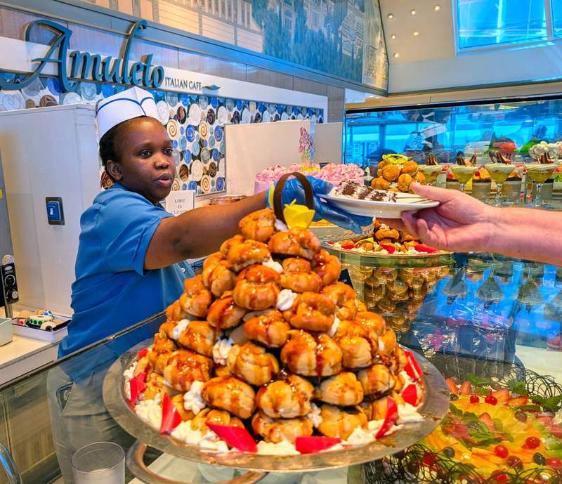 A woman hands a decadent dessert to a cruise passenger