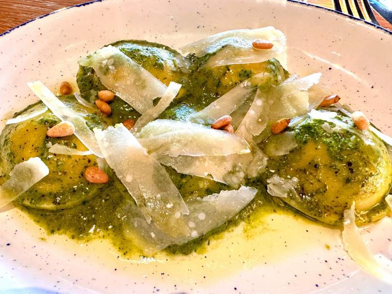 Ravioli in a pesto sauce with pine nuts and shaved parmesan cheese