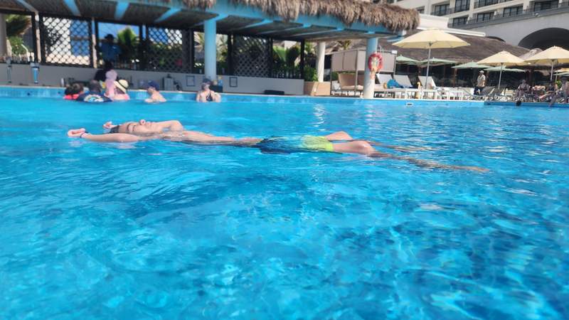 A boy floating atop a large swimming pool