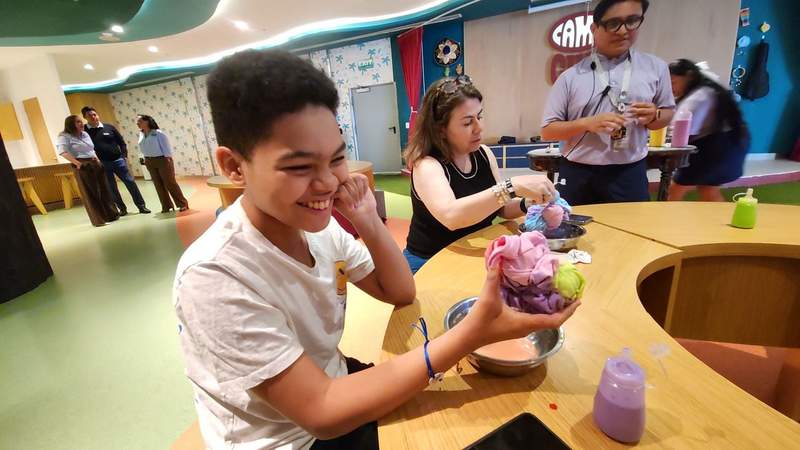 A boy holding a balled-up tie-dye t-shirt