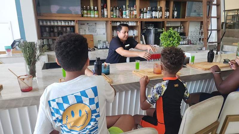 Two children and an adult at a counter with various glassware