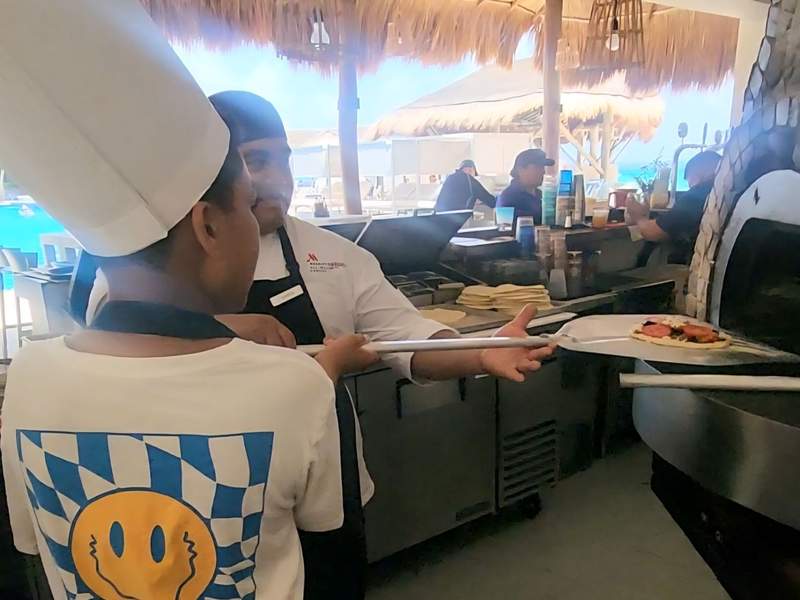 An adult and child placing a pizza in a brick oven