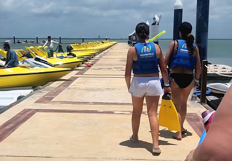 Two people walking on a dock lined with speedboats