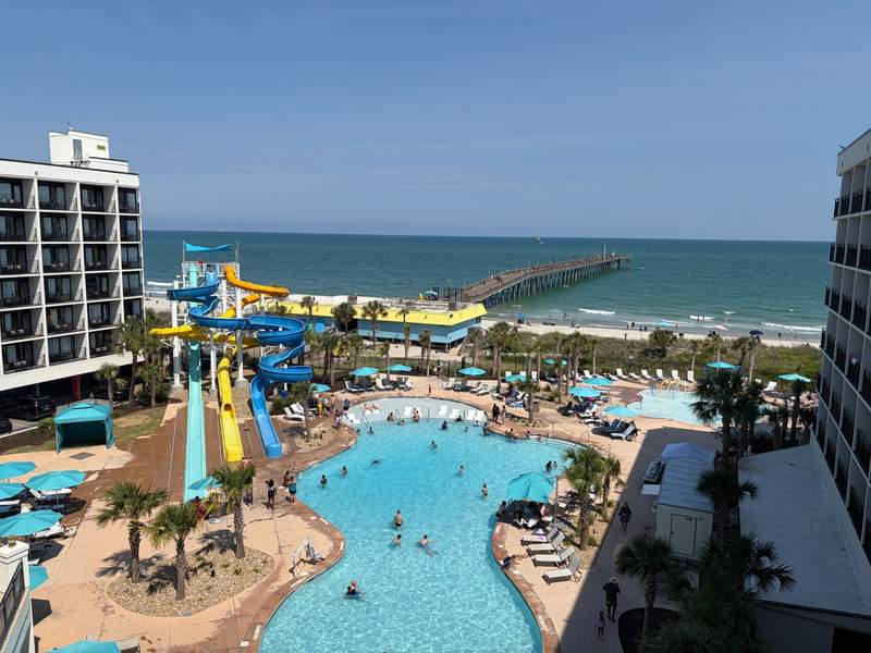 An elevated balcony view overlooking the expansive resort pool area at Ellie Beach Resort in Myrtle Beach.