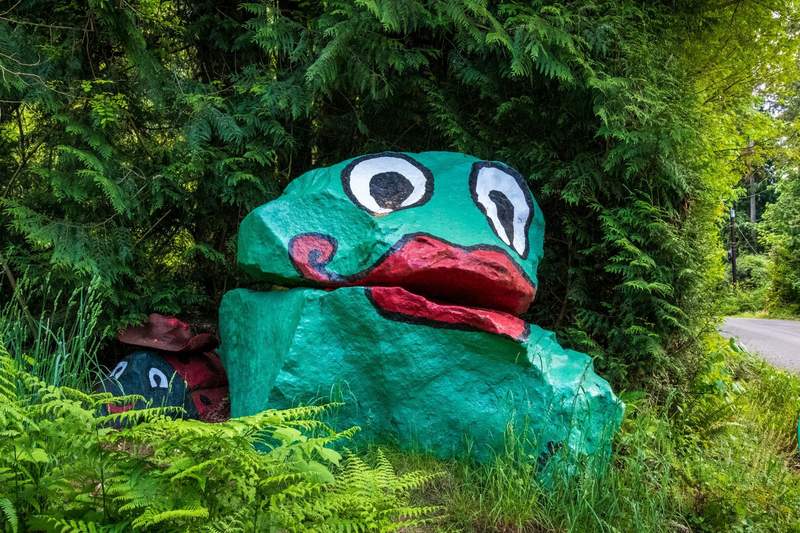 A large landmark roadside boulder painted to look like a green frog