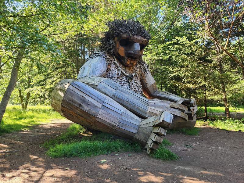 Huge outdoor wooden troll sculpture built from recycled materials in the park woods