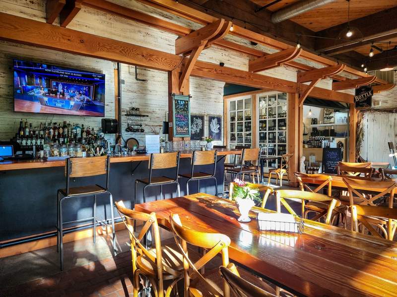 Warm cafe interior with wine bottles on display and large tables