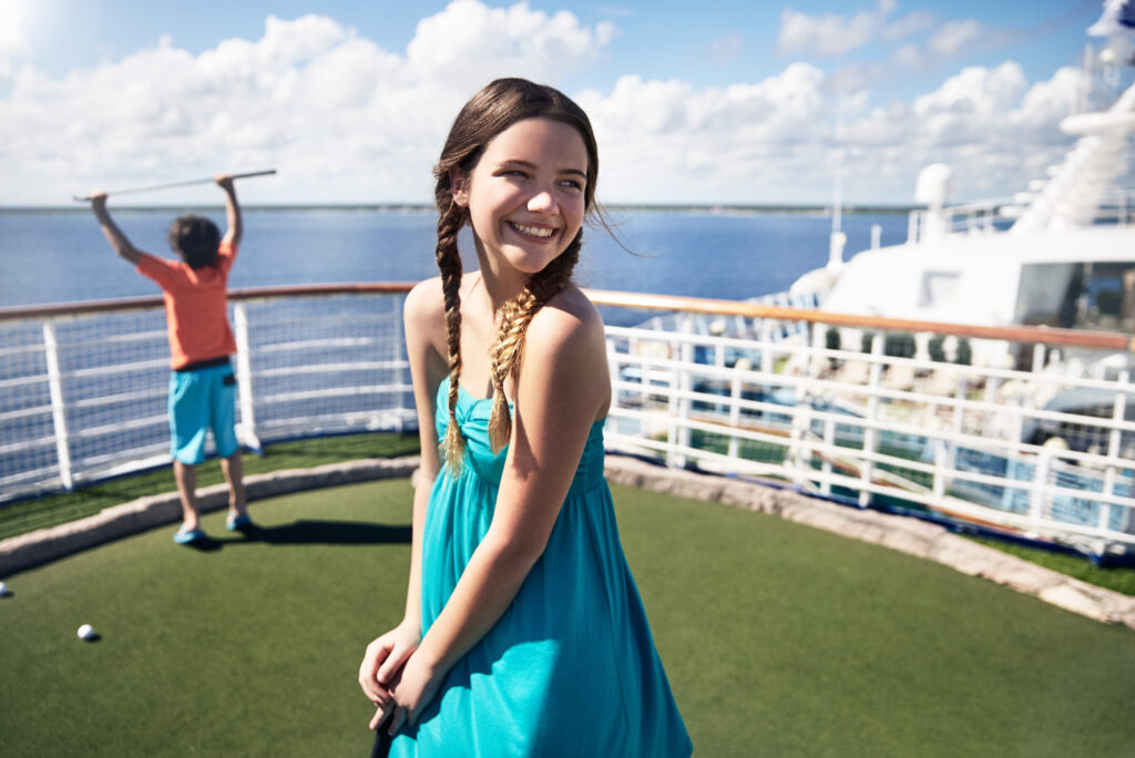 Girl and boy playing mini golf on deck of a Princess Cruise Line ship.