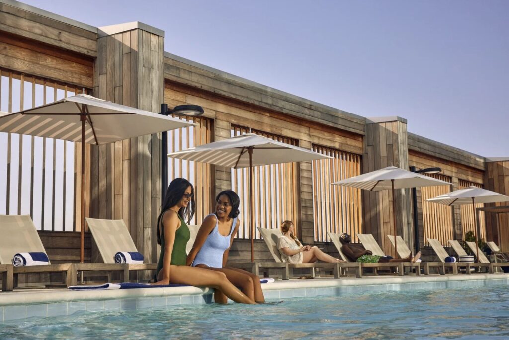 Two women sitting on the side of a large pool at a Hilton hotel