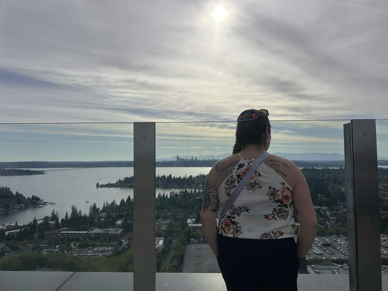 A woman on 31st floor patio overlooking a city landscape at dusk.
