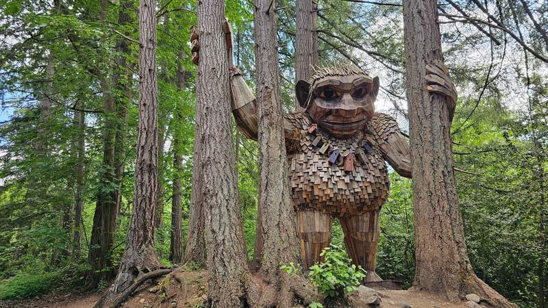 A fourteen-foot outdoor public art sculpture of a friendly troll built from recycled wood slats along a forest trail.