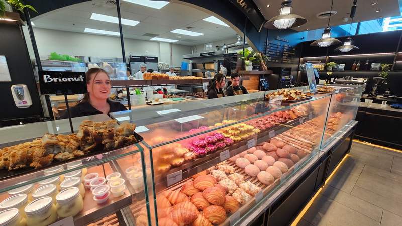 A bright bakery display case filled with croissants, tarts, and golden European and Asian fusion pastries.