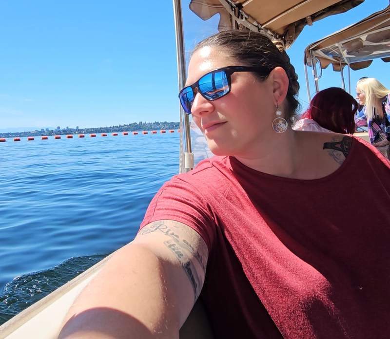A woman sitting on the deck of an electric boat, gazing out at a wide expanse of blue water.