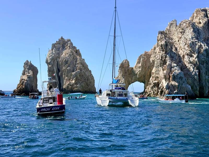 Small boats sailing past the iconic El Arco rock formation at Land's End.