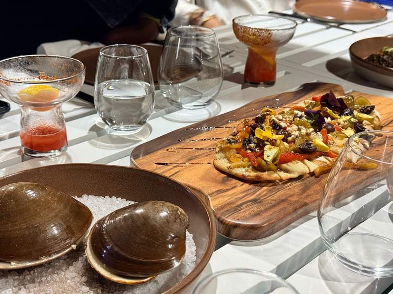 Handcrafted Mezcal cocktails and a freshly baked flatbread pizza on a Kadun patio table.