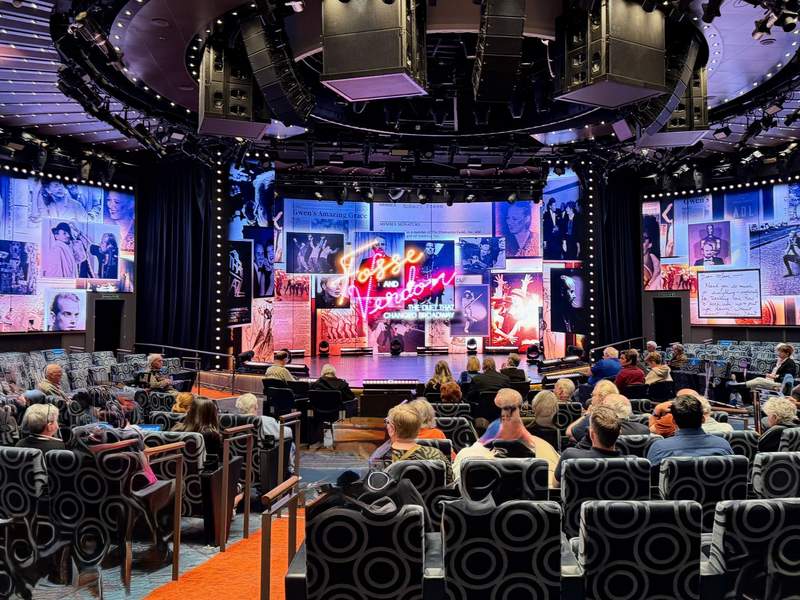 An audience seated in the theater on Koningsdam cruise ship watching a stage production titled Fosse and Verdon with large digital screens.