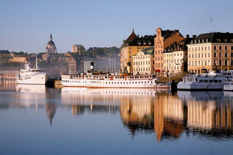 Boats lining the waterfront along Skeppsbron, with the historic buildings of Stockholm’s Old Town in the background.