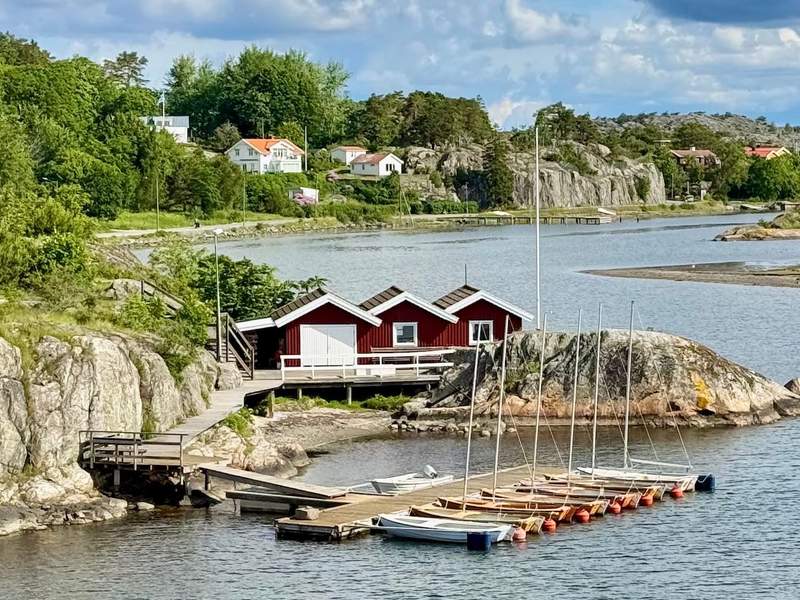 Red boathouses and boats along the water, viewed from the bridge between Styrsö and Donsö in Gothenburg’s Southern Archipelago.