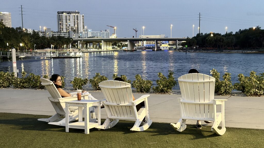 White Adirondack chairs with the Tampa evening skyline in the background