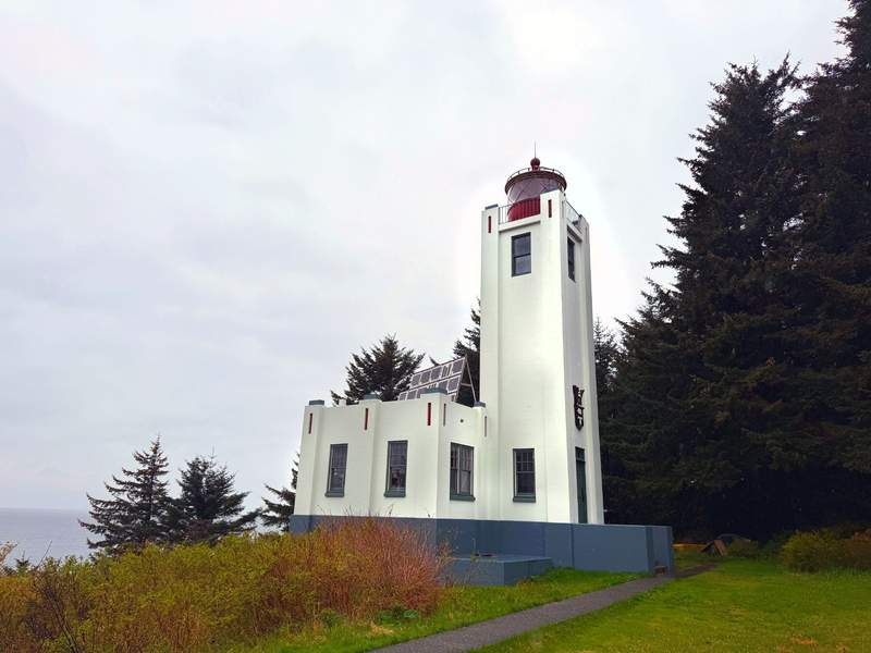Historic Art Deco concrete Sentinel Island Lighthouse perched on a forested island along Lynn Canal near Juneau, Alaska.