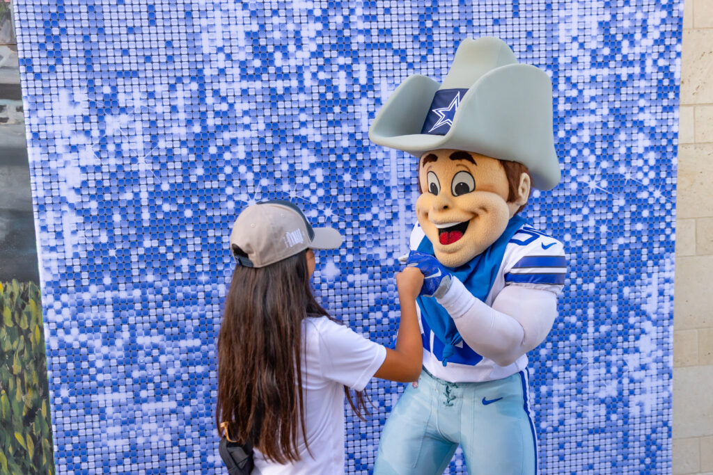 Tween ager bumping fists with Rowdy, the Dallas Cowboys mascot