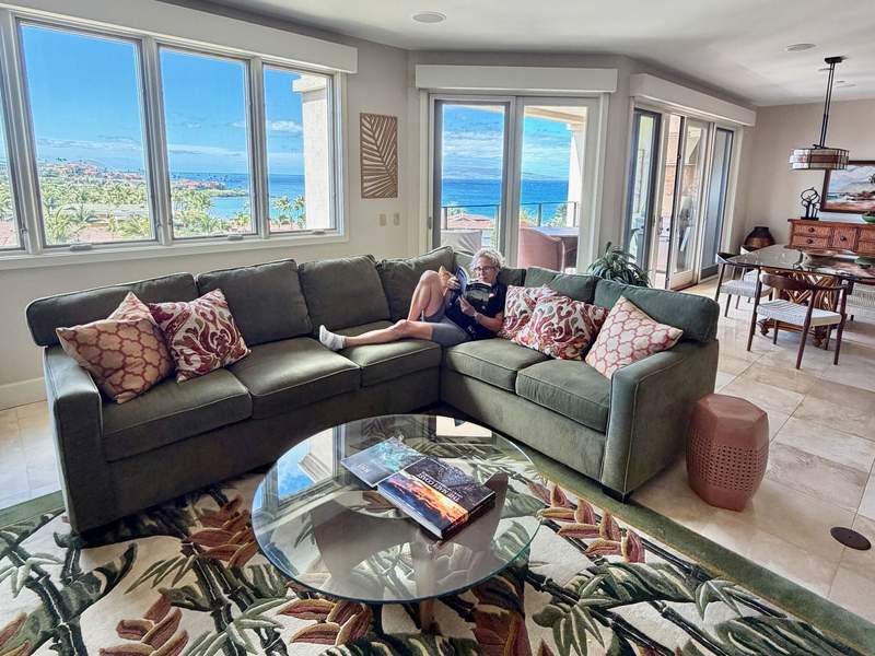 Kim sitting on green/gray sectional sofa in Living room at Wailea Beach Villas with ocean-view windows.
