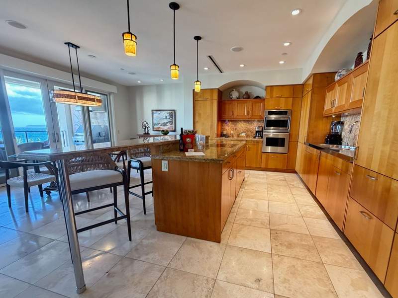 Fully stocked kitchen at Wailea Beach Villas with granite island, stainless appliances and ocean-view dining nook