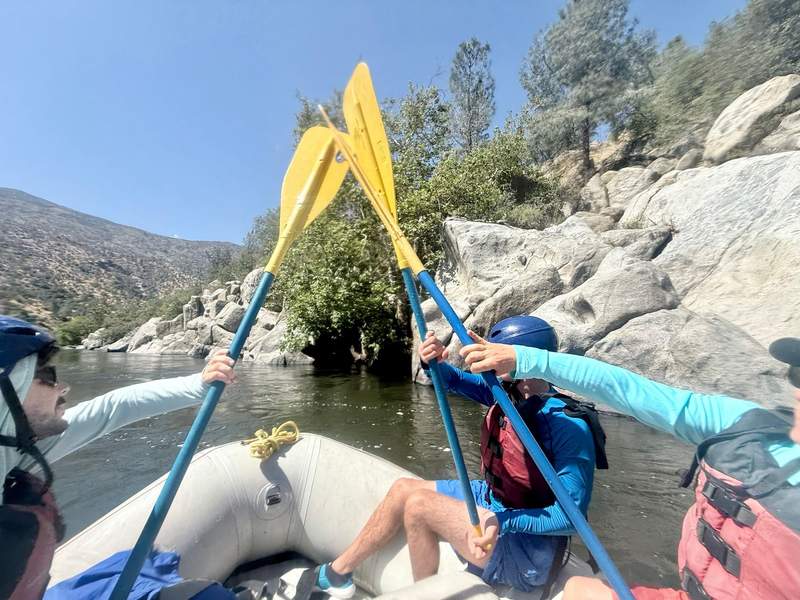 Author’s family raising their paddles in the front of the raft on the Kern River.