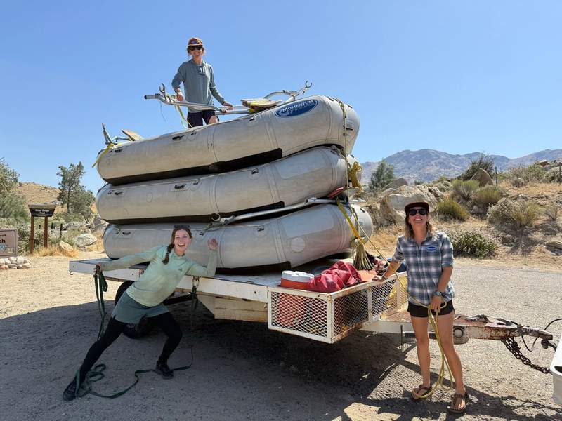 3 women prepping a trailer with rafts stacked on it.