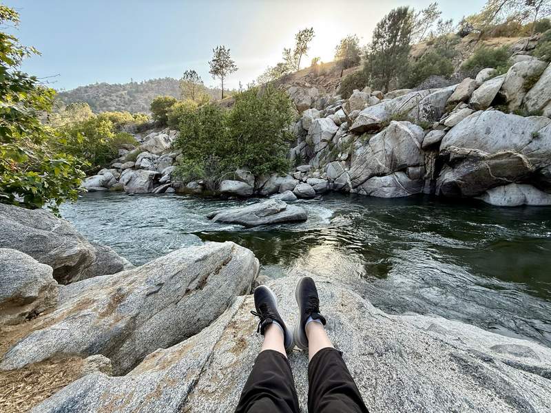 Author’s legs stretched out on a rock overlooking the river near sunset.