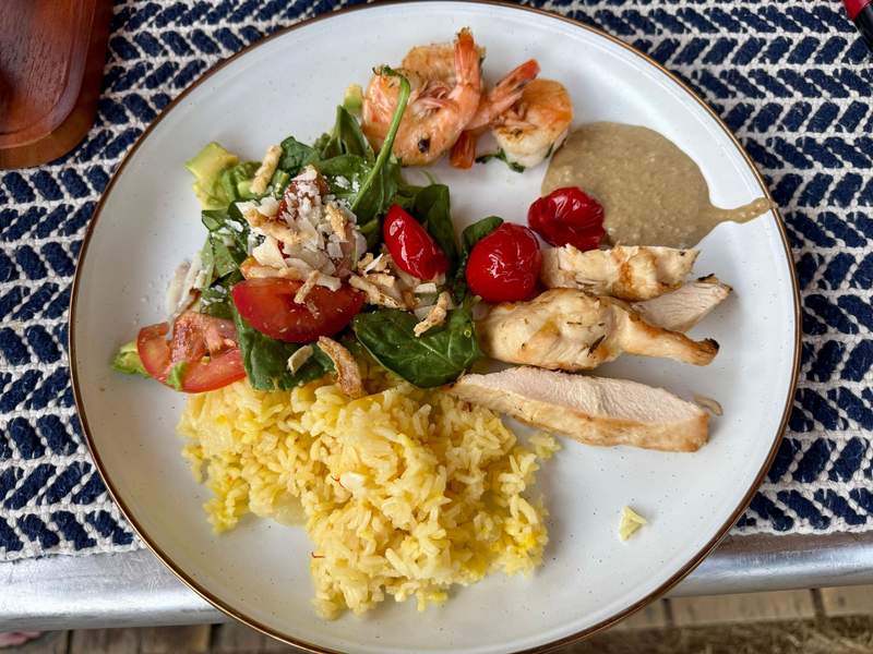 Plate of chicken, rice, salad and shrimp.