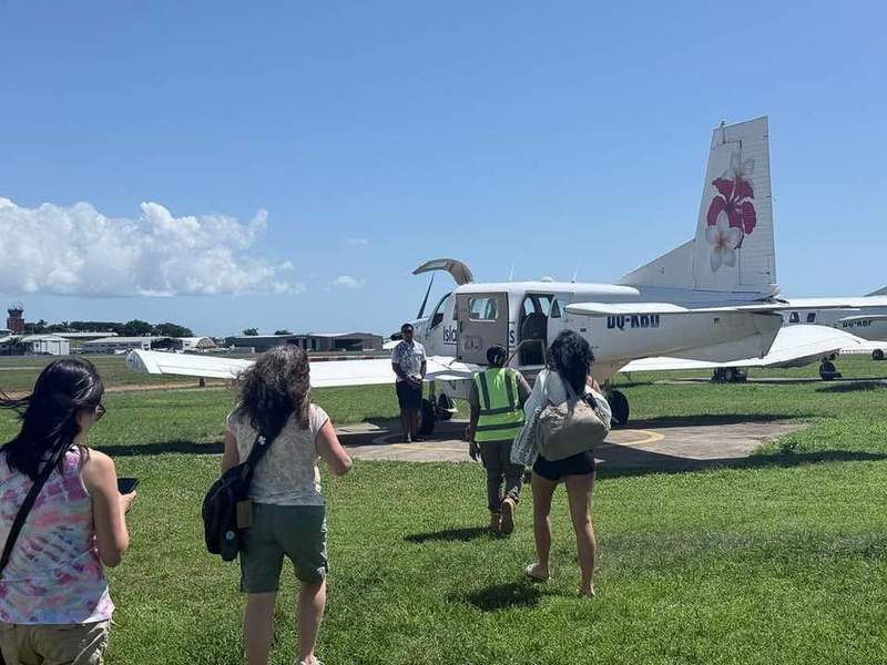 women boarding a small plane on grass airstrip in Fiji