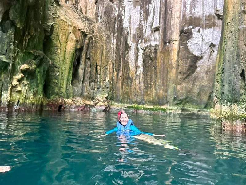 woman in blue long sleeve shirt swimming in a cave