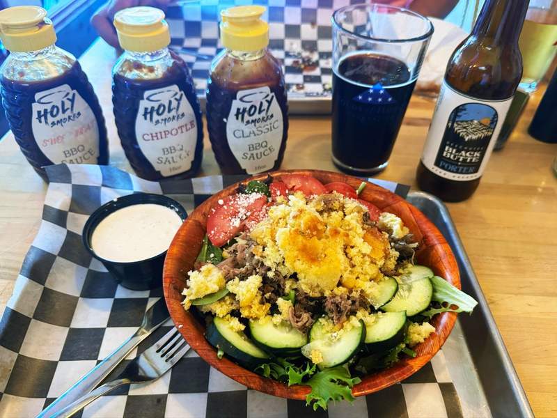 Pulled pork salad, a glass of beer and three BBQ sauces.