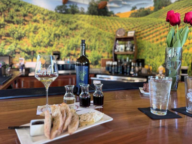A tasting flight of three wines with a small plate of bread and cheese.