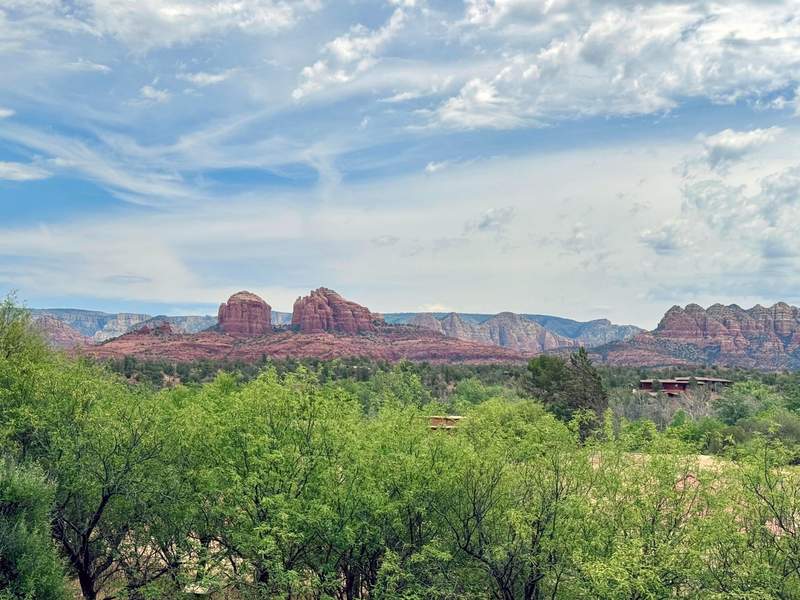 View of the iconic red rocks of Sedona, Arizona with green bushes in the forefront.