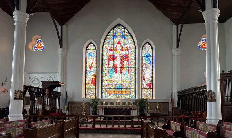 Interior view of a historic cathedral in downtown Nassau Bahamas highlighting detailed stained glass windows and traditional wooden pews.