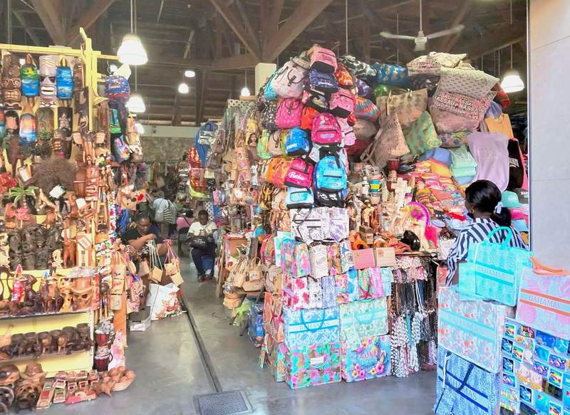 Interior view of the Nassau Straw Market in the Bahamas showing local vendor stalls stacked high with handwoven bags and wood crafts.