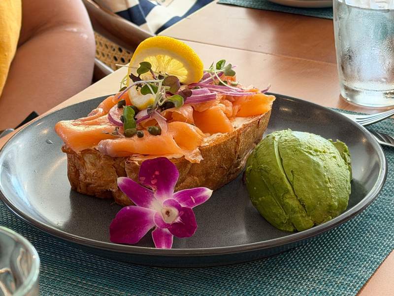 Smoked salmon toast served with fresh sliced avocado and edible orchid garnish at Tamarind Marketplace at the British Colonial Nassau.