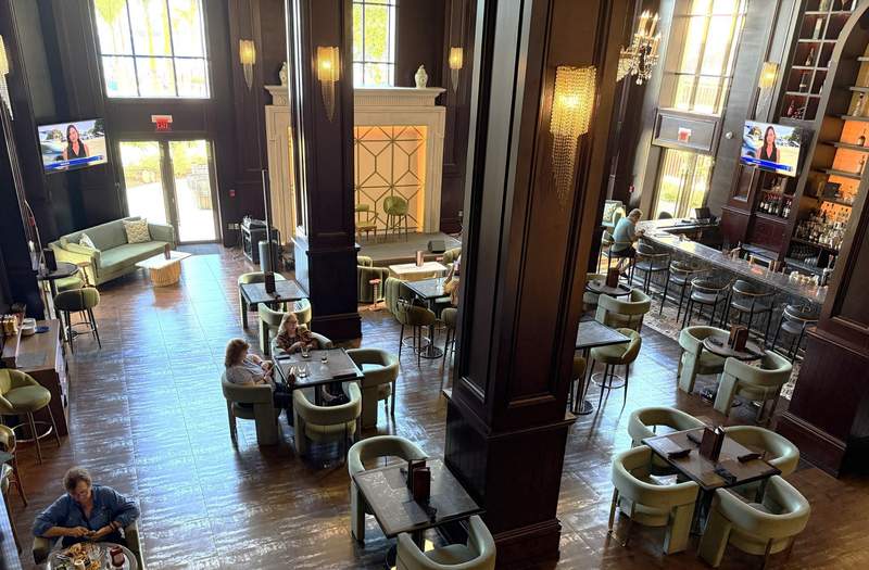 Interior view of the Woodes Rogers Tavern at British Colonial Nassau with vaulted ceilings dark mahogany accents green velvet chairs and a long marble bar.