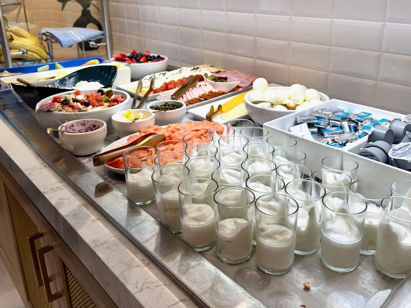 The breakfast buffet at the Hilton Times Square with White yogurt in classes, lox, cream cheese, hard boiled eggs, meats and fruit.