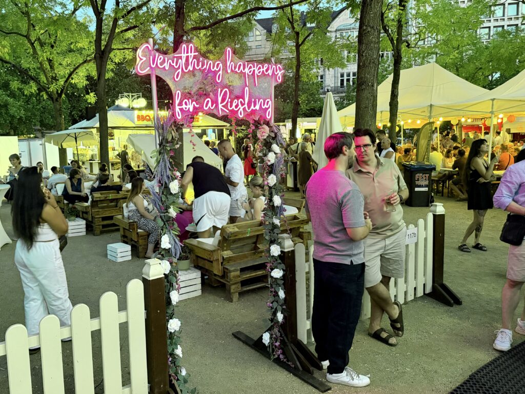 People gathered in front of a pink neon sign at the Rheingau wine festival in Wiesbaden Germany