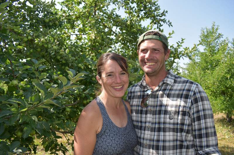 Dave and Melissa Dobernigg standing next to each other next to an apple tree.