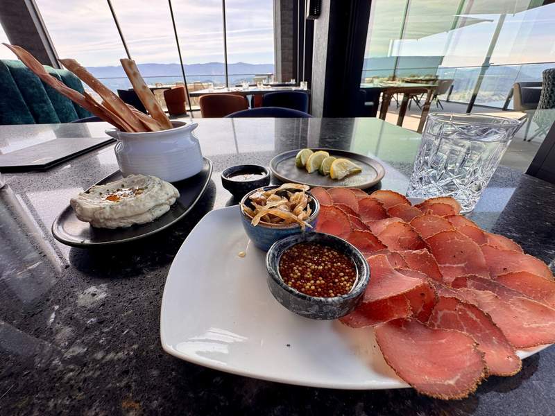 Charcuterie plate with humus and flat bread sticks with a glass of water in an architecturally stunning restaurant.