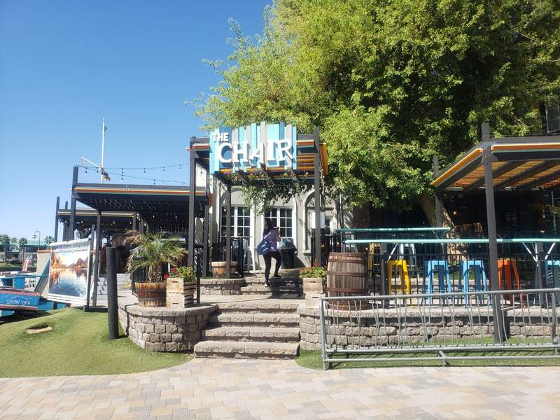 Waterfront view of The Chair restaurant in the English Village, featuring outdoor patio dining along the blue waters of Lake Havasu.