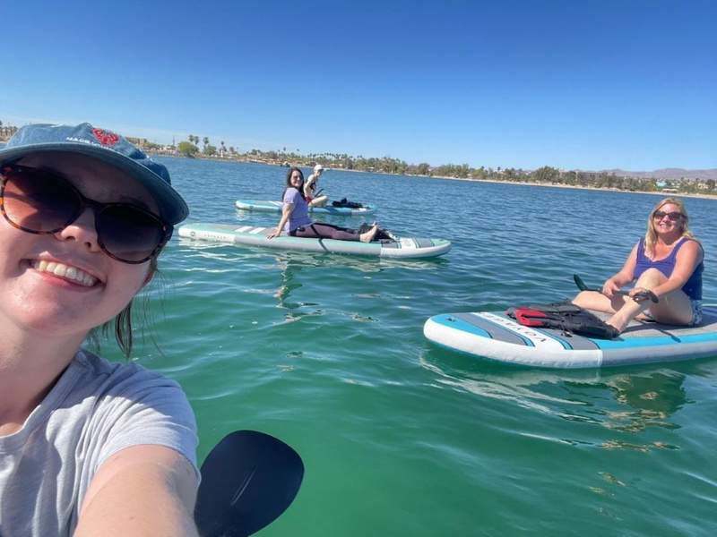 A group of friends paddleboarding together on the calm blue waters of Lake Havasu on a sunny day.