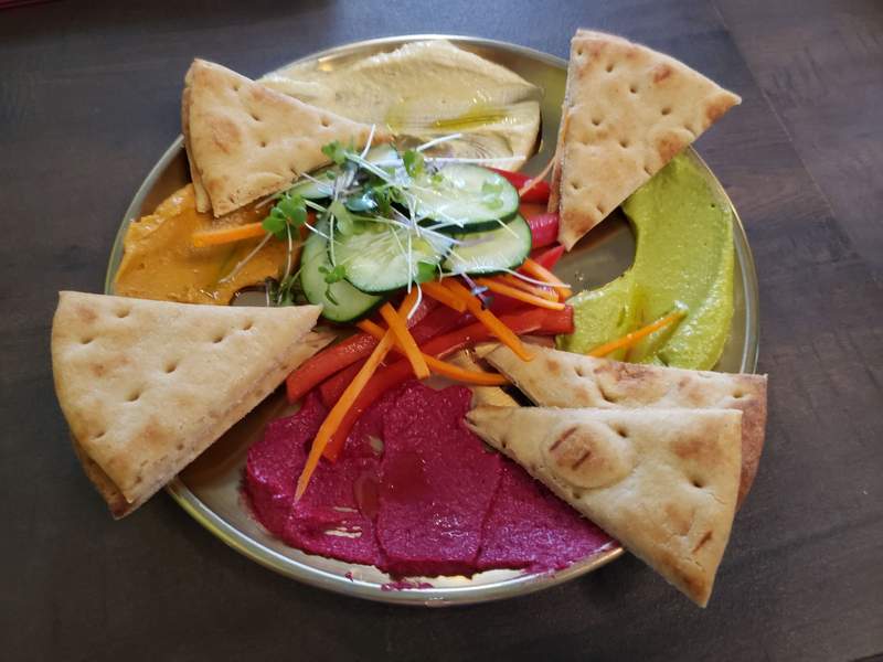 A healthy lunch meal with a fresh smoothie bowl and wraps served at an outdoor table at Siddhartha's Garden.