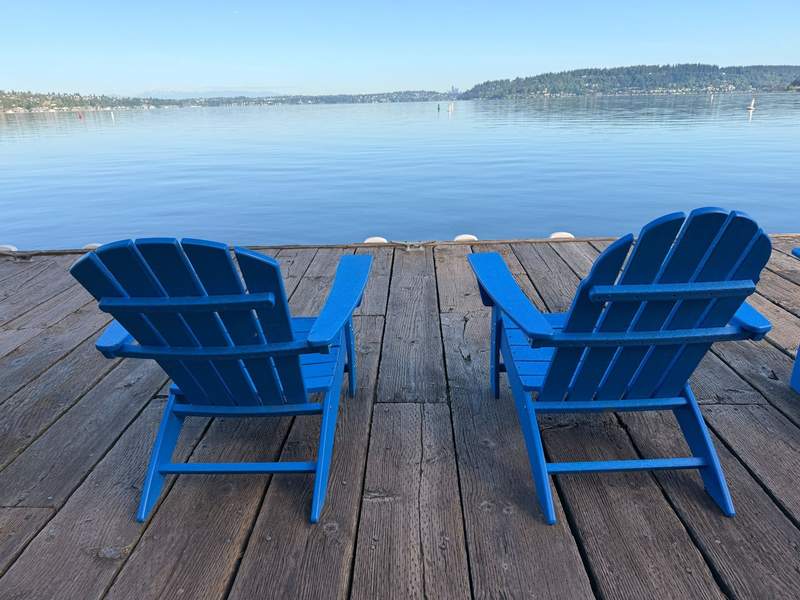 Two blue Adirondack chairs on a dock overlooking Lake Washington.